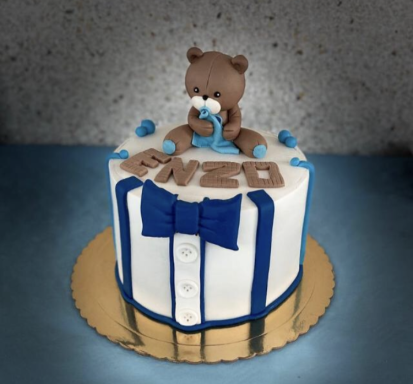 TARTA DE BAUTISMO Tarta decorada con un oso de fondant y nombre "Enzo" en tonos azules y blancos.