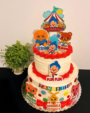 TARTA DEL PAYASO PLIM PLIM Pastel de cumpleaños de dos niveles decorado con personajes infantiles y colores vibrantes.