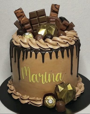 TARTA CON CHOCOLATES Tarta decorada con chocolate, bombones y el nombre "Martina" en la parte frontal.