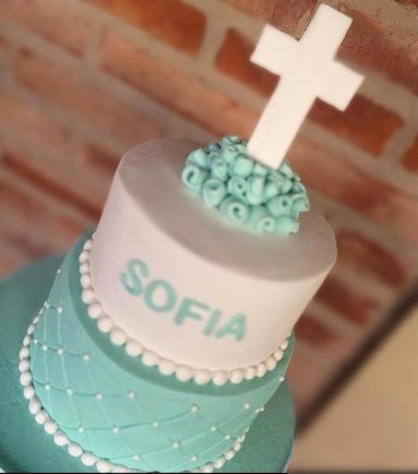 TARTA DE COMUNIÓN Tarta decorada en tonos aqua con una cruz blanca y el nombre "SOFIA".
