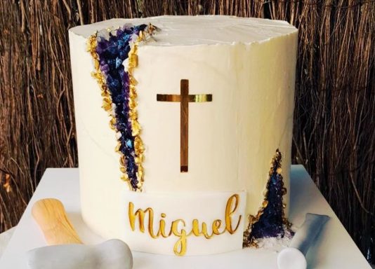 TARTA COMUNIÓN Tarta blanca decorada con una cruz y el nombre "Miguel" en dorado.