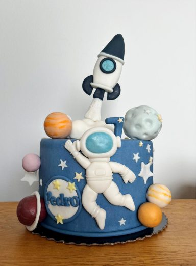 TARTA ESPACIAL Tarta temática espacial con un astronauta, cohete y planetas coloridos.