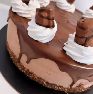 TARTA DE AVELLANAS Tarta de chocolate con cobertura brillante y decoraciones de nata y trozos de chocolate.