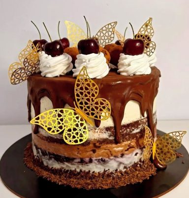 TARTA SELVA NEGRA ESPECIAL Tarta de chocolate decorada con cerezas, crema y mariposas doradas.