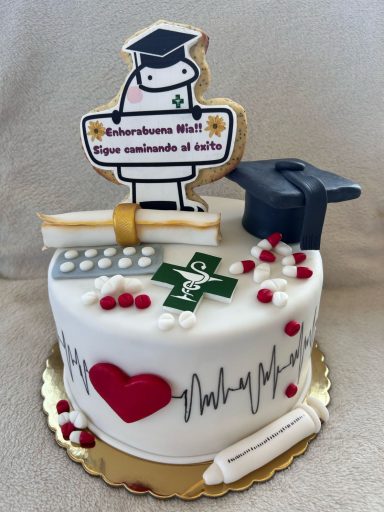 TARTA PARA FARMACEUTICA Tarta decorada con un graduado, un gorro, un diploma y elementos médicos.