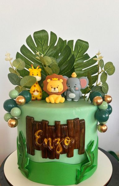 TARTA SELVA Tarta decorada con animales de safari y el nombre "Enzo" en un fondo verde.