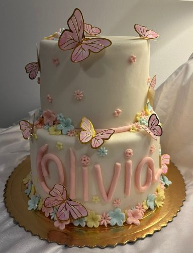 TARTA EN TONO PASTEL Pastel de cumpleaños de dos pisos decorado con mariposas y el nombre "Olivia".